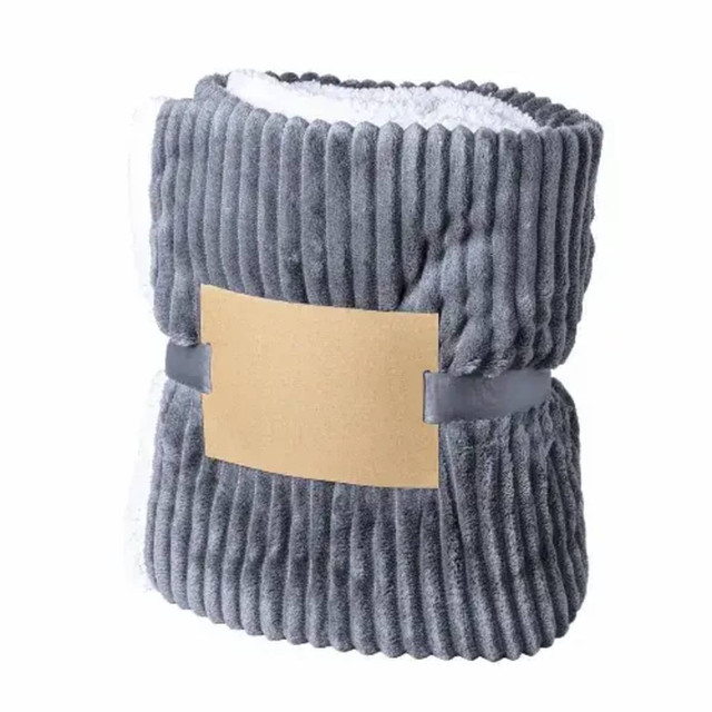 A grey, ribbed blanket with a soft, white lining, secured with a simple band. Features a logo on the band.
