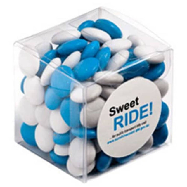 A clear cube filled with blue and white chocolate beans, with a circular branding logo on the front. A clear cube filled with blue and white chocolate beans, with a circular branding logo on the front.
