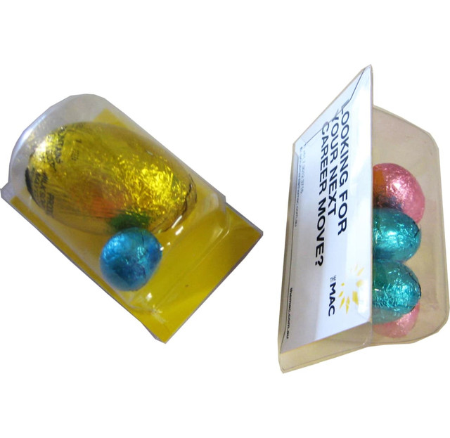A transparent packaging filled with colourful Easter eggs: gold, blue, and pink, accompanied by a branded card. A transparent packaging filled with colourful Easter eggs: gold, blue, and pink, accompanied by a branded card.