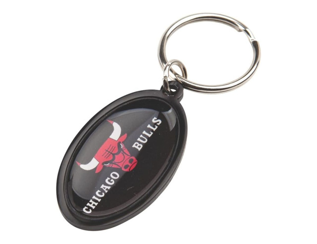 An oval keyring featuring a black background and a bull logo with a red and white design. It has a metal ring attachment.