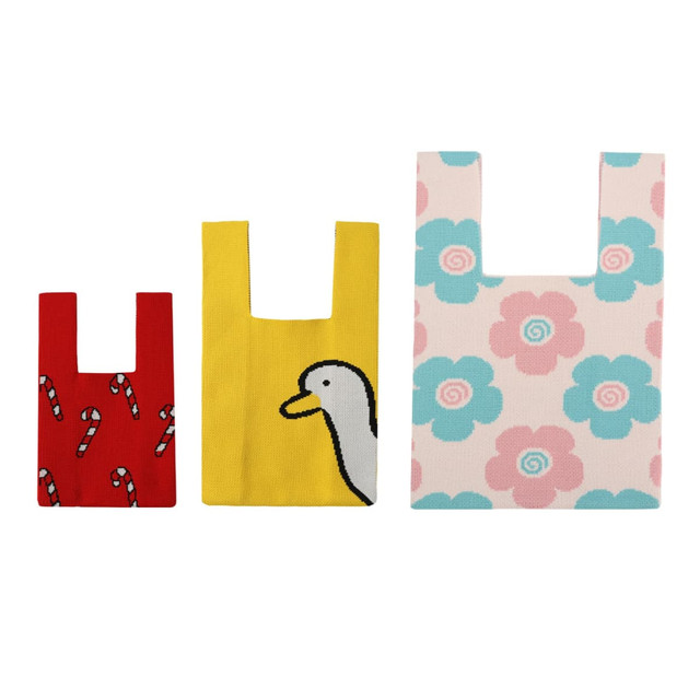 Three knitted tote bags in red with candy canes, yellow with a duck, and pink with floral patterns. Each has a logo.