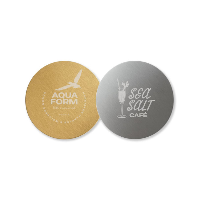 A round metal coaster featuring a gold finish on one side and a silver finish on the other, both with logos.