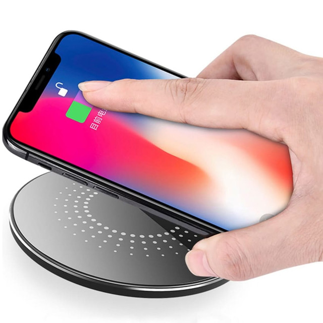 A wireless charger in black with a hand placing a smartphone on it, featuring a circular design and a logo.