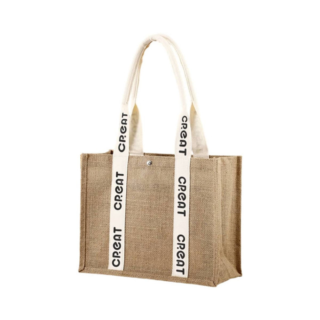 A jute tote bag in natural brown with cream-coloured handles featuring printed text and a snap closure.