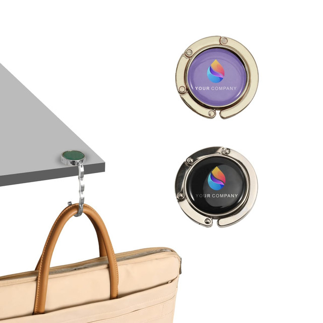 A round, foldable desk hook in silver and green, featuring a logo, designed for hanging bags.