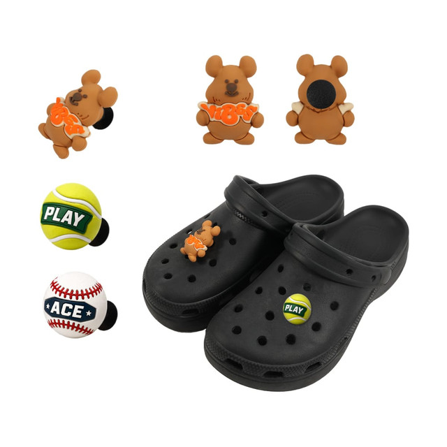 Black clog shoes with 3D brown bear charms and two sports-themed charms, including a tennis ball and a baseball.