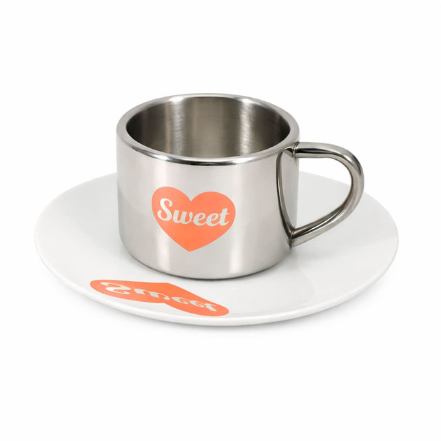 A stainless steel coffee mug with a mirror finish and an orange heart design, accompanied by a white saucer.