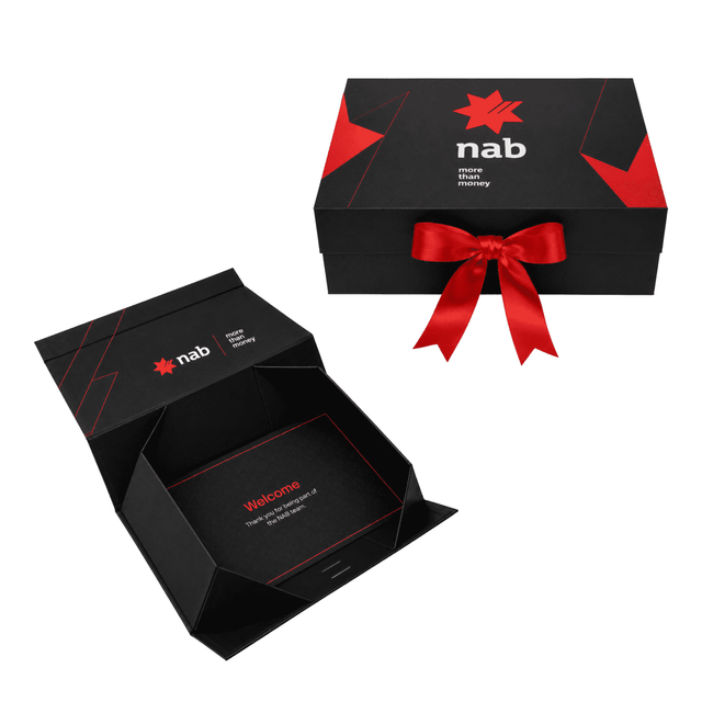 A small black gift box with a red ribbon, featuring a logo and a welcome message inside.