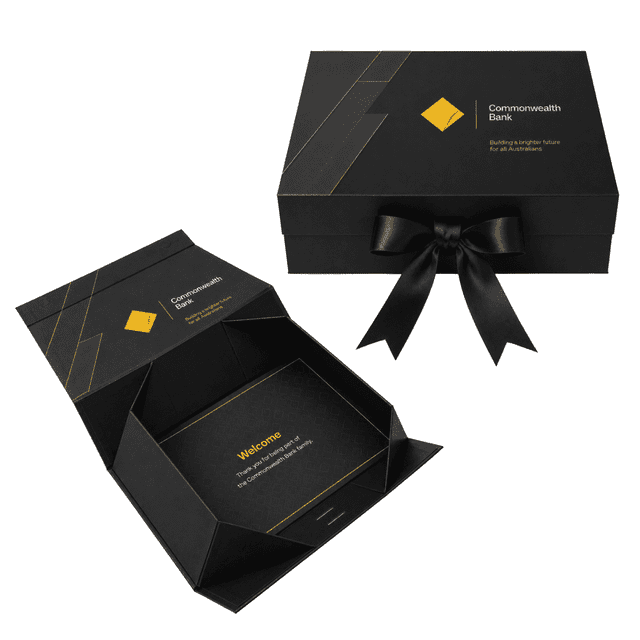 A large black gift box with a gold geometric design and black ribbon, featuring an interior greeting card.