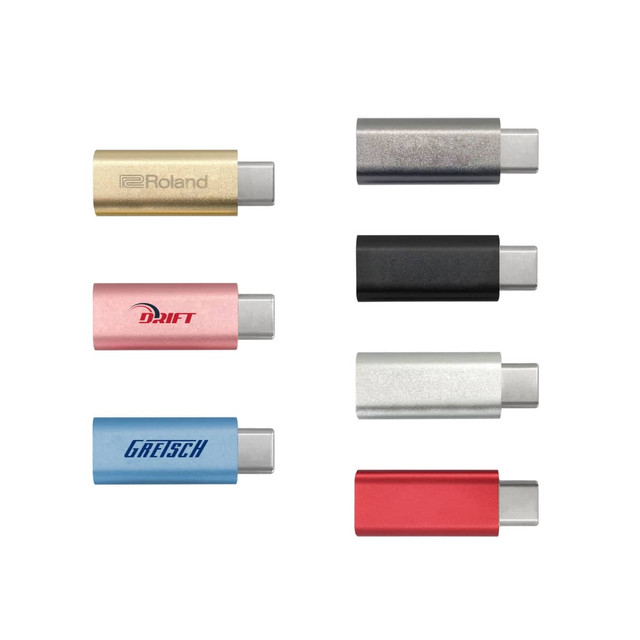 A collection of six USB data blockers in various colours: gold, pink, black, silver, blue, and red. Each item has a logo.