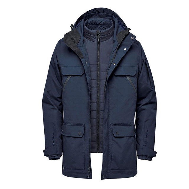 A navy blue 5-in-1 system jacket with a detachable inner layer and multiple pockets. It features a logo on the front.