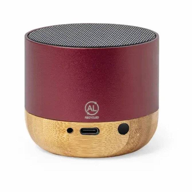 A red speaker made of recycled aluminium and bamboo, featuring a textured speaker grille and ports at the base.