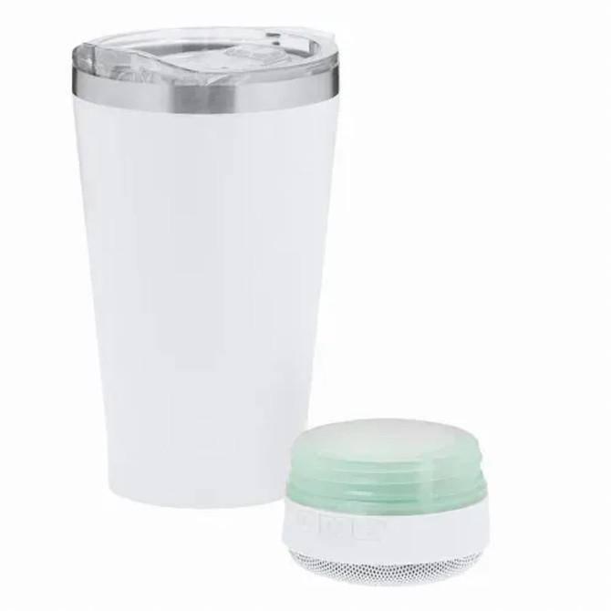 An insulated white cup with a silver lid next to a mint green speaker. Both items feature branding.