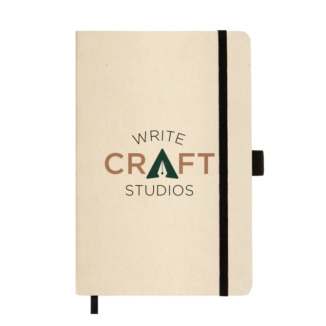 A beige A5 notebook with a black elastic band and a logo featuring the words "WRITE CRAFT STUDIOS."