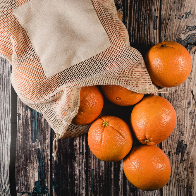 A mesh produce bag filled with fresh oranges. The bag features a natural-colored fabric and a drawstring closure.