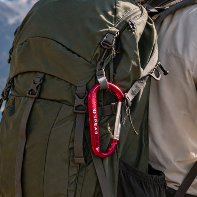 A red 6cm carabiner attached to a dark green backpack, showcasing practical design features.