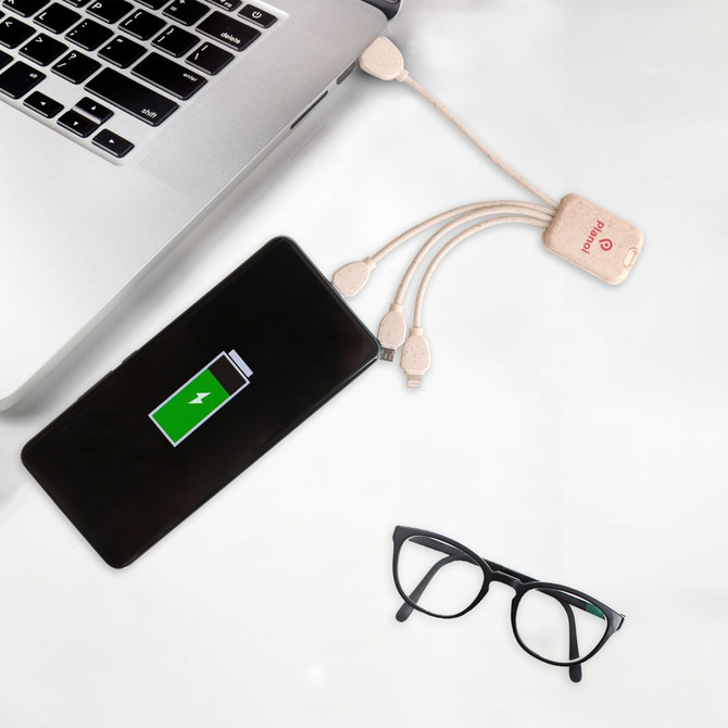 A square-shaped wheat straw charging cable in beige, connected to a smartphone and a laptop, with glasses nearby.