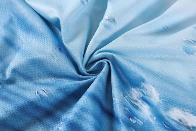 A blue sublimated polyester spandex fabric with a textured pattern, featuring cloud-like designs.