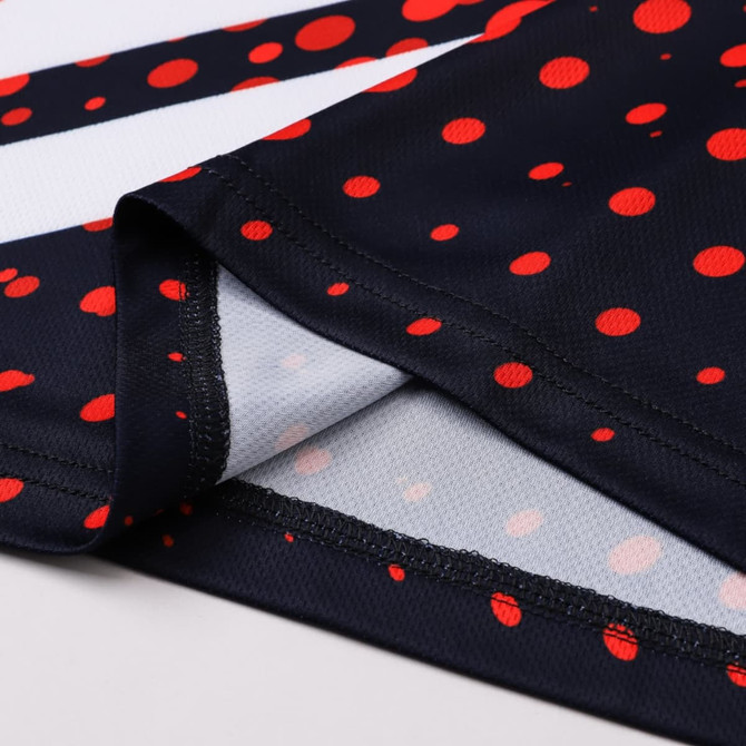 A football jersey in navy with red polka dots, featuring a branded logo and a smooth fabric finish.
