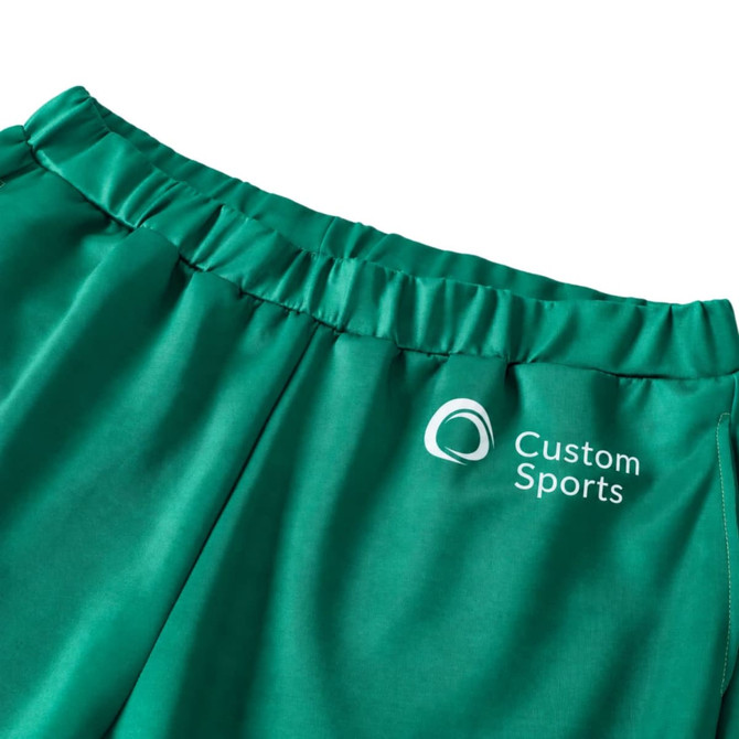 Green unisex adult sports shorts made of 100% polyester, featuring an elastic waistband and a logo.