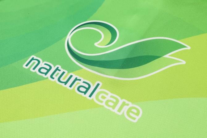 A green polo shirt featuring a subtle wave design and a logo with the word "naturalcare."