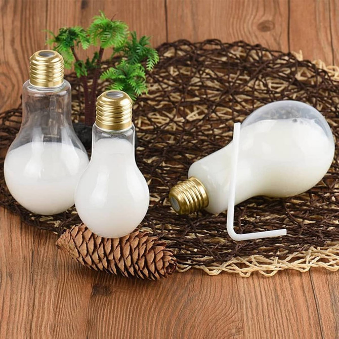 A drink bottle shaped like a light bulb, clear with a gold top, featuring a straw and a glossy finish.