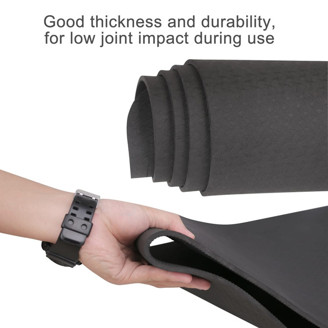 A premium TPE yoga mat in black, showcasing its thickness and durability, with a hand holding one edge.