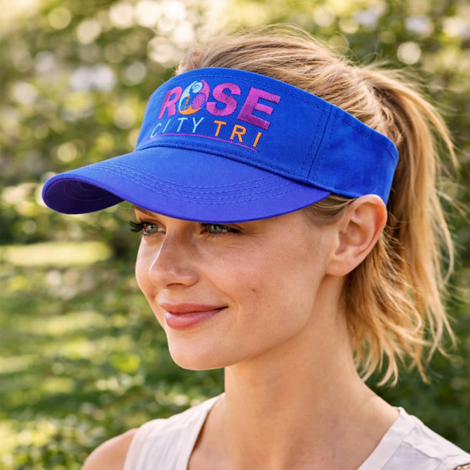 A blue sport visor featuring a logo, positioned on a woman's head in an outdoor setting.