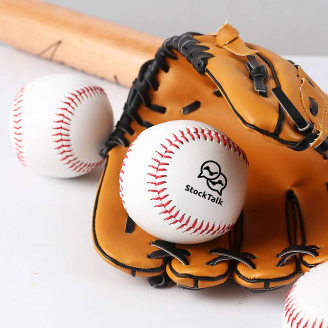 A white training baseball with red stitching rests in a brown baseball glove, alongside another similar baseball.