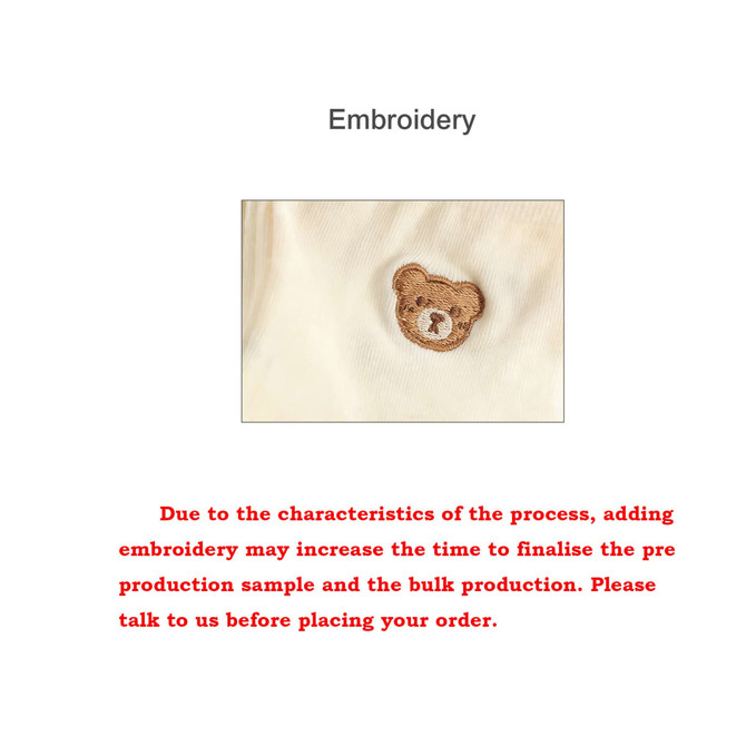 A close-up of a cream coloured fabric featuring a brown teddy bear embroidery.