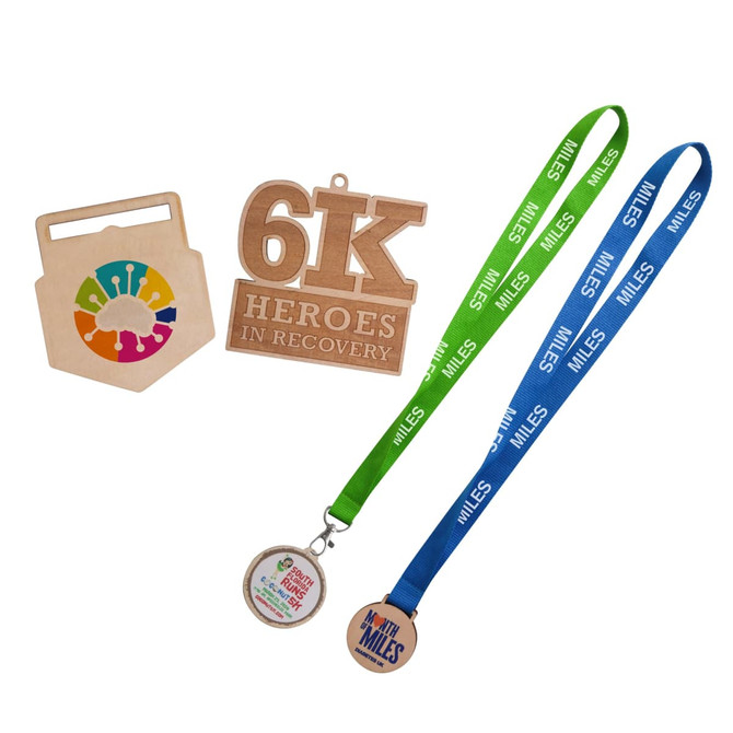Custom-shaped wooden medals in natural wood tones, with colourful lanyards in green and blue. Includes a logo.