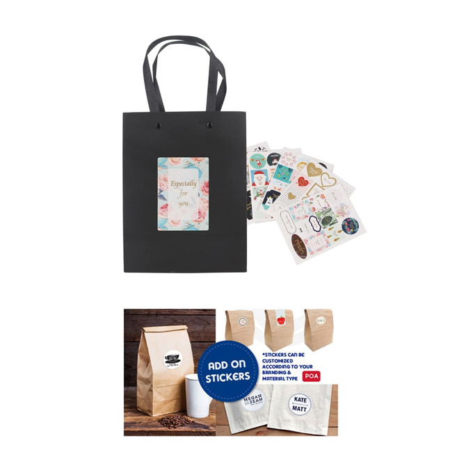 A small black vertical paper bag with knitted handles and a decorative tag, accompanied by various stickers.