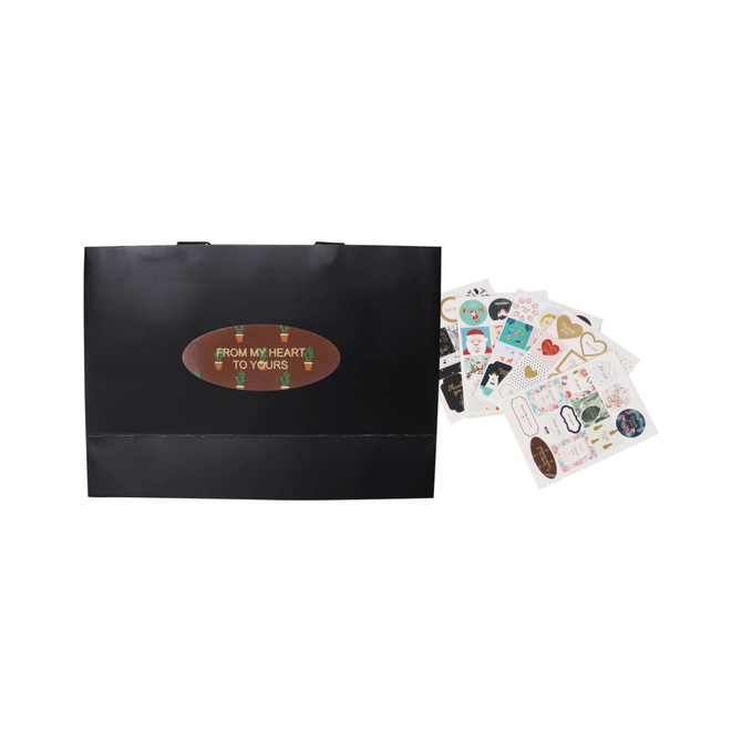 A large black paper bag with flat handles beside various decorative stickers.