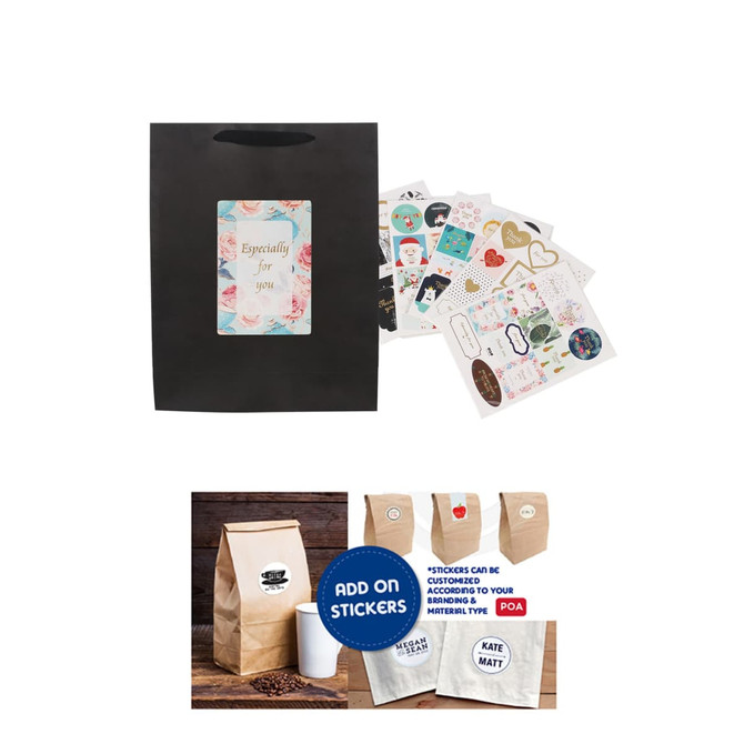 A medium vertical black paper bag with a fabric flat handle, alongside assorted colourful stickers and a kraft bag.