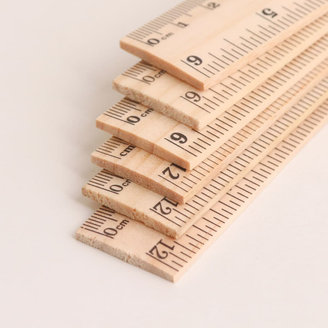 A dual scale wooden ruler with measurements in centimetres and inches, featuring a natural wood finish.