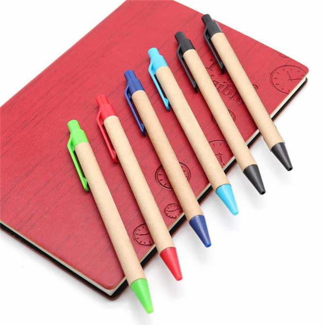 Kraft paper pens in green, red, blue, black, and turquoise arranged on a red notebook with a logo.