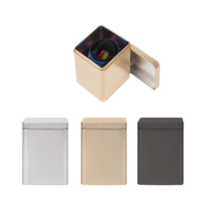 A square tin box in silver, gold, and dark green, featuring an open lid revealing colourful contents inside.