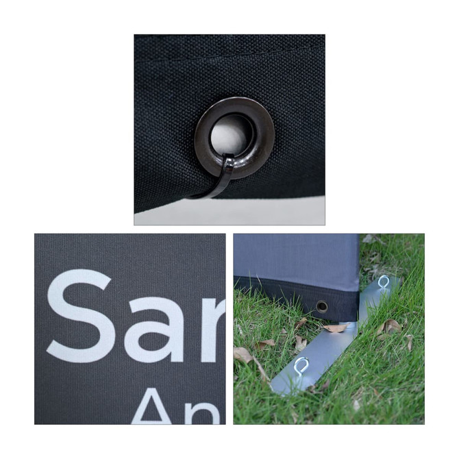 Close-up of a black Sidewalk Cafe Barrier featuring a grommet, a logo, and a base anchor on grass.