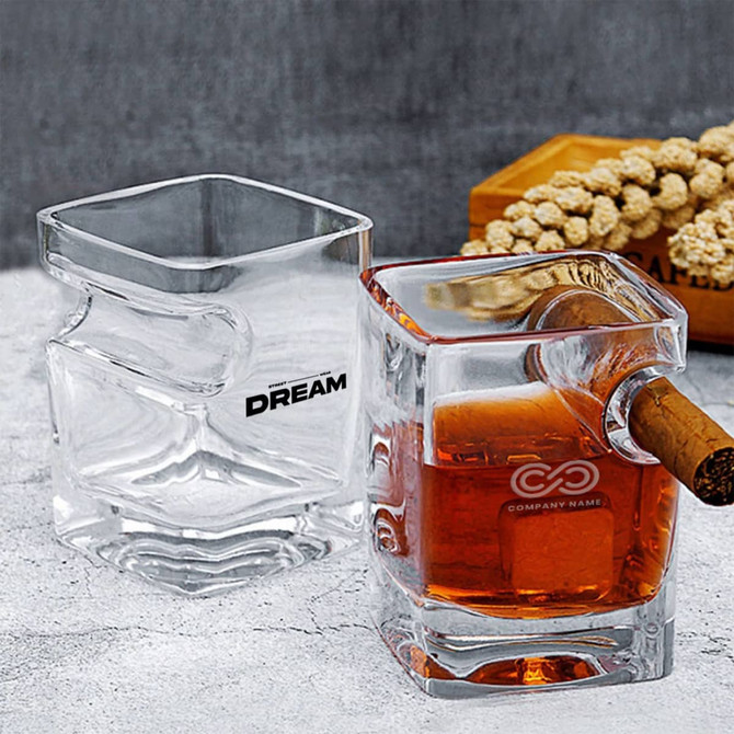 A whiskey glass set featuring square-shaped designs with one glass holding amber liquid and a cigar inserted.