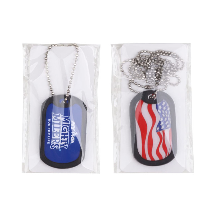A dog tag set featuring a blue tag with a logo and a red and white striped flag design, presented in packaging.