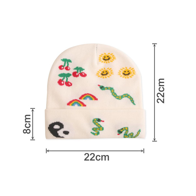 A white knitted beanie with colourful designs featuring cherries, suns, rainbows, and snakes, along with a logo.