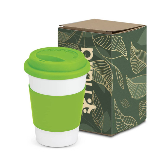 A coffee cup featuring a white body with a bright green silicone lid and sleeve, presented beside a patterned box.