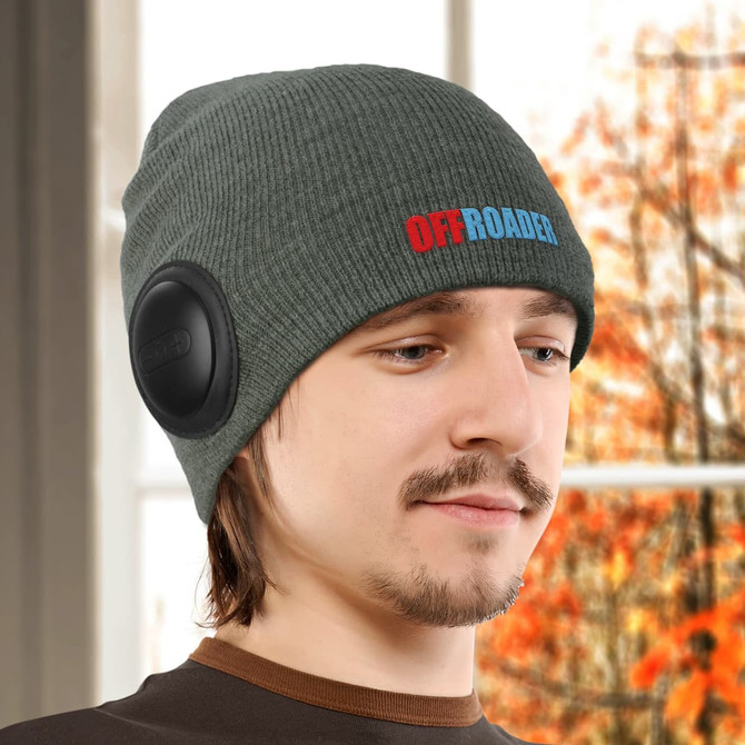 A green knitted beanie featuring black speakers on the sides and a colourful logo.