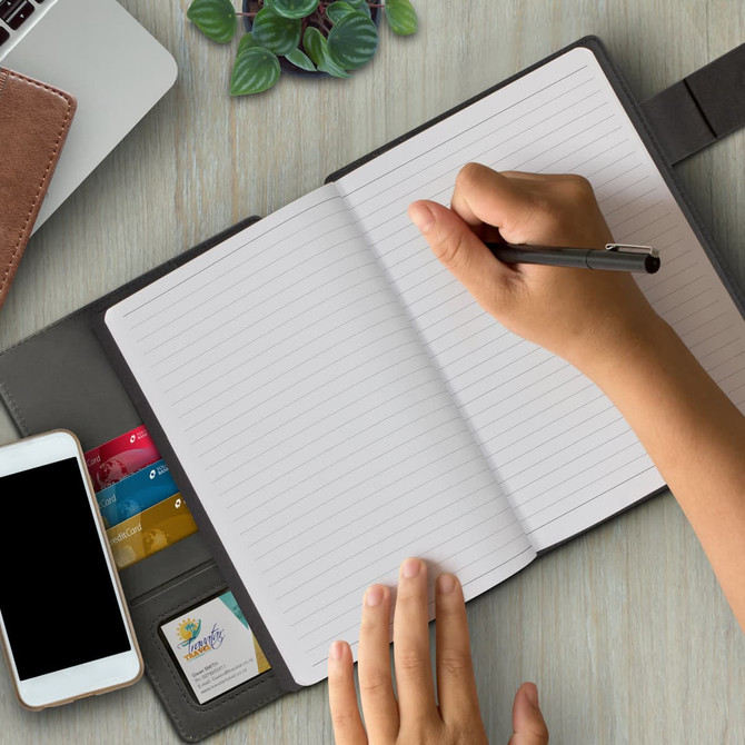 A black Stockholm Portfolio with a hand writing in a lined notebook. Also features a phone and card slots.