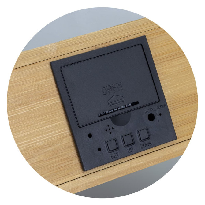A black wireless charging clock with buttons, set on a light bamboo surface.