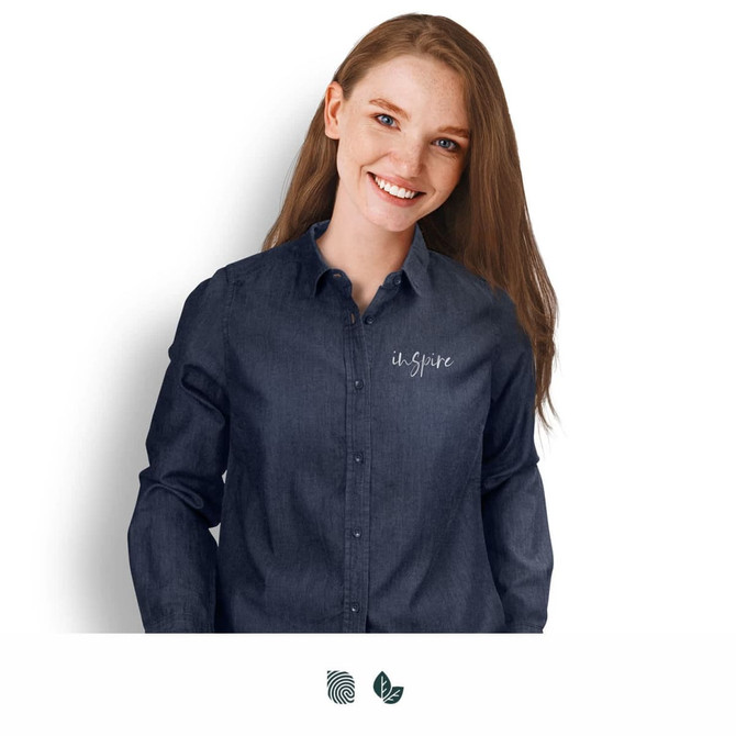 A woman wears a stylish dark denim button-up shirt featuring a logo on the chest.