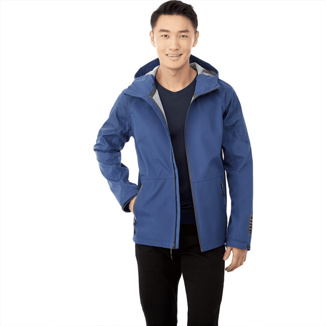 A blue softshell jacket with a hood, worn by a smiling man, featuring a logo on the front.