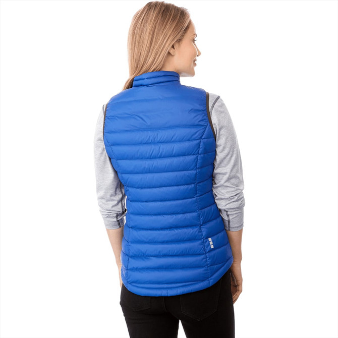 A woman wearing a blue puffer vest, featuring a high collar and a fitted design, viewed from the back.