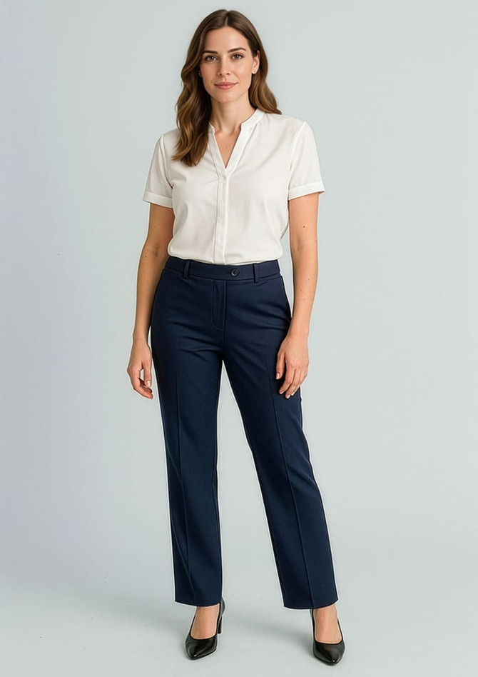 A woman stands wearing a white shirt and navy relaxed pants. The outfit features a logo on the pants.