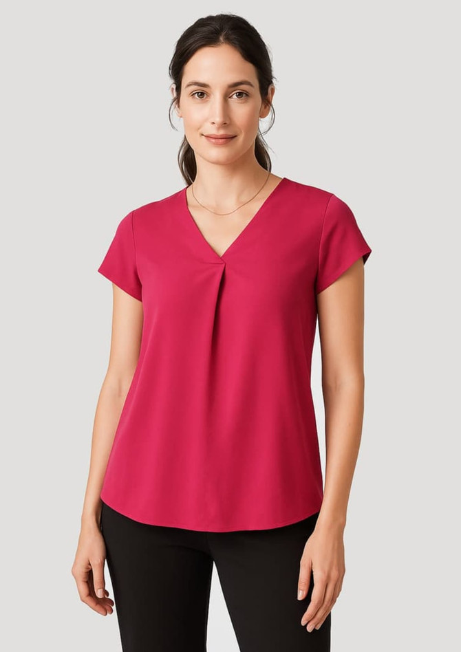 A woman models a fuchsia pink Women's Kayla V-Neck Pleat Blouse, featuring a pleat detail and short sleeves.